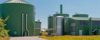Biomass energy plant with green anaerobic digester tanks and storage silos under a clear sky