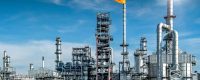 Petrochemical refinery with flare stack burning against a blue sky, distillation columns and storage tanks