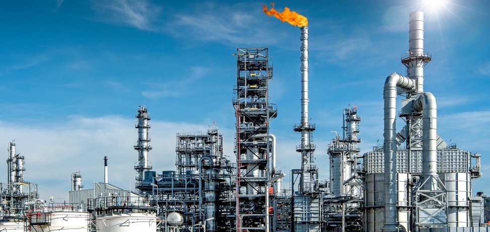 Petrochemical refinery with flare stack burning against a blue sky, distillation columns and storage tanks